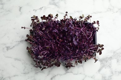 Fresh radish microgreens on white marble table, top view