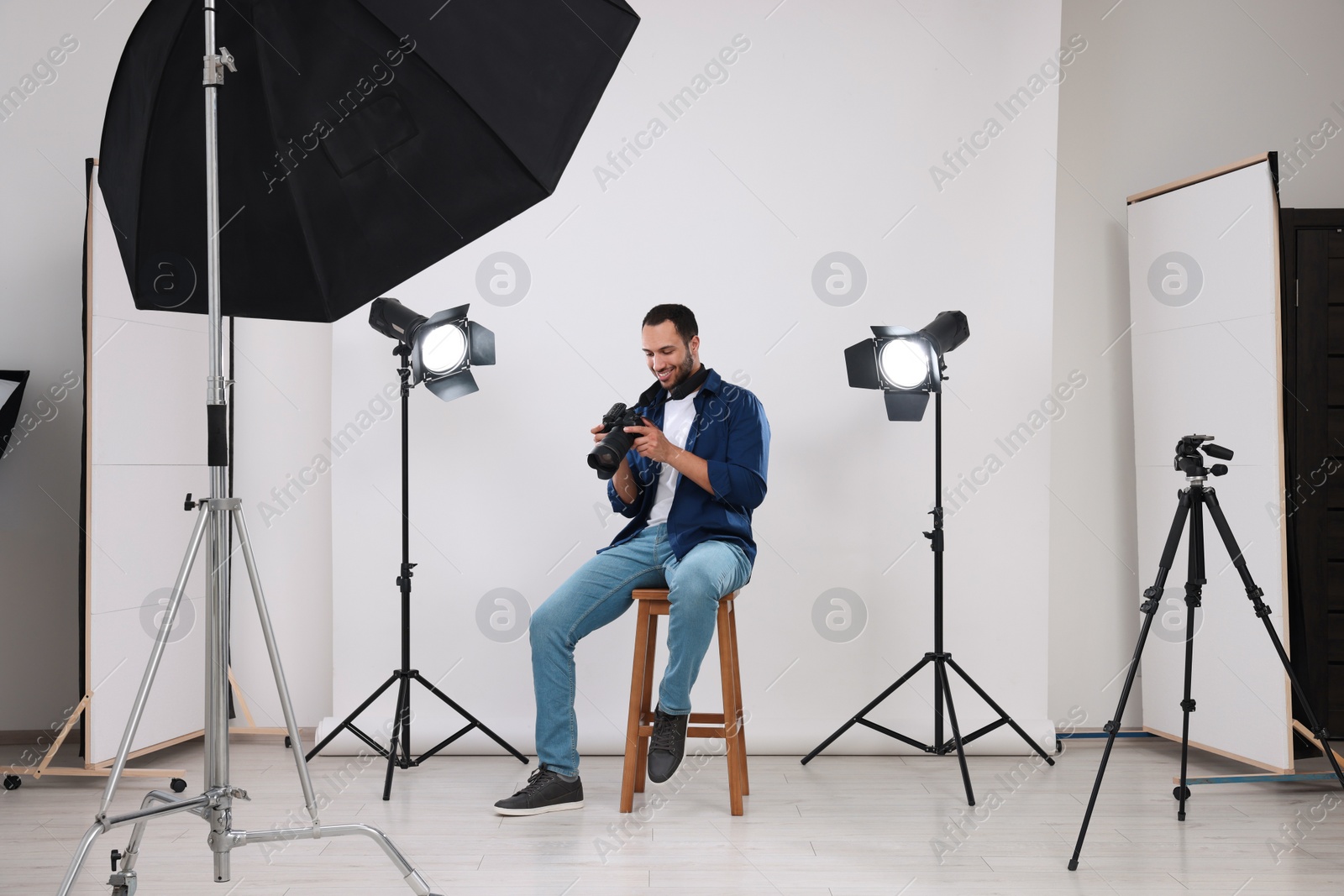 Photo of Young professional photographer with camera in modern photo studio