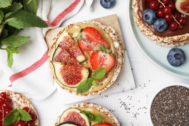 Photo of Tasty crispbreads with different toppings on white table, flat lay