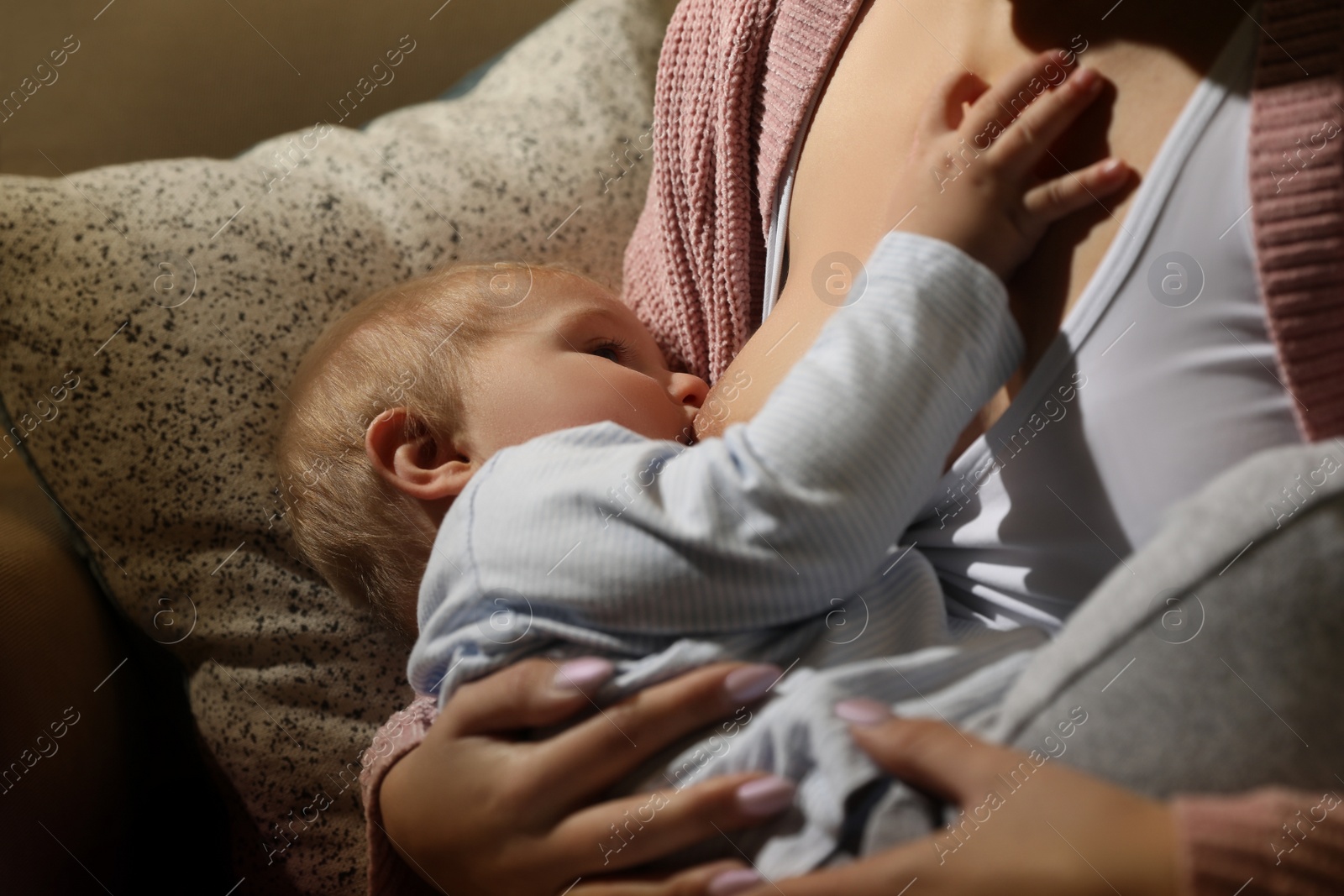 Photo of Woman breastfeeding her little baby at home, closeup