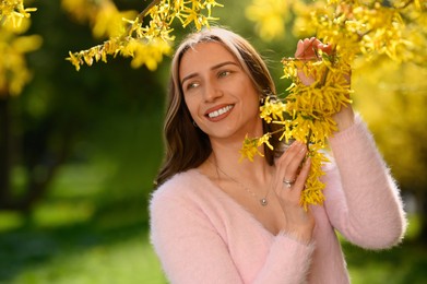 Beautiful young woman near blossoming shrub on spring day, space for text