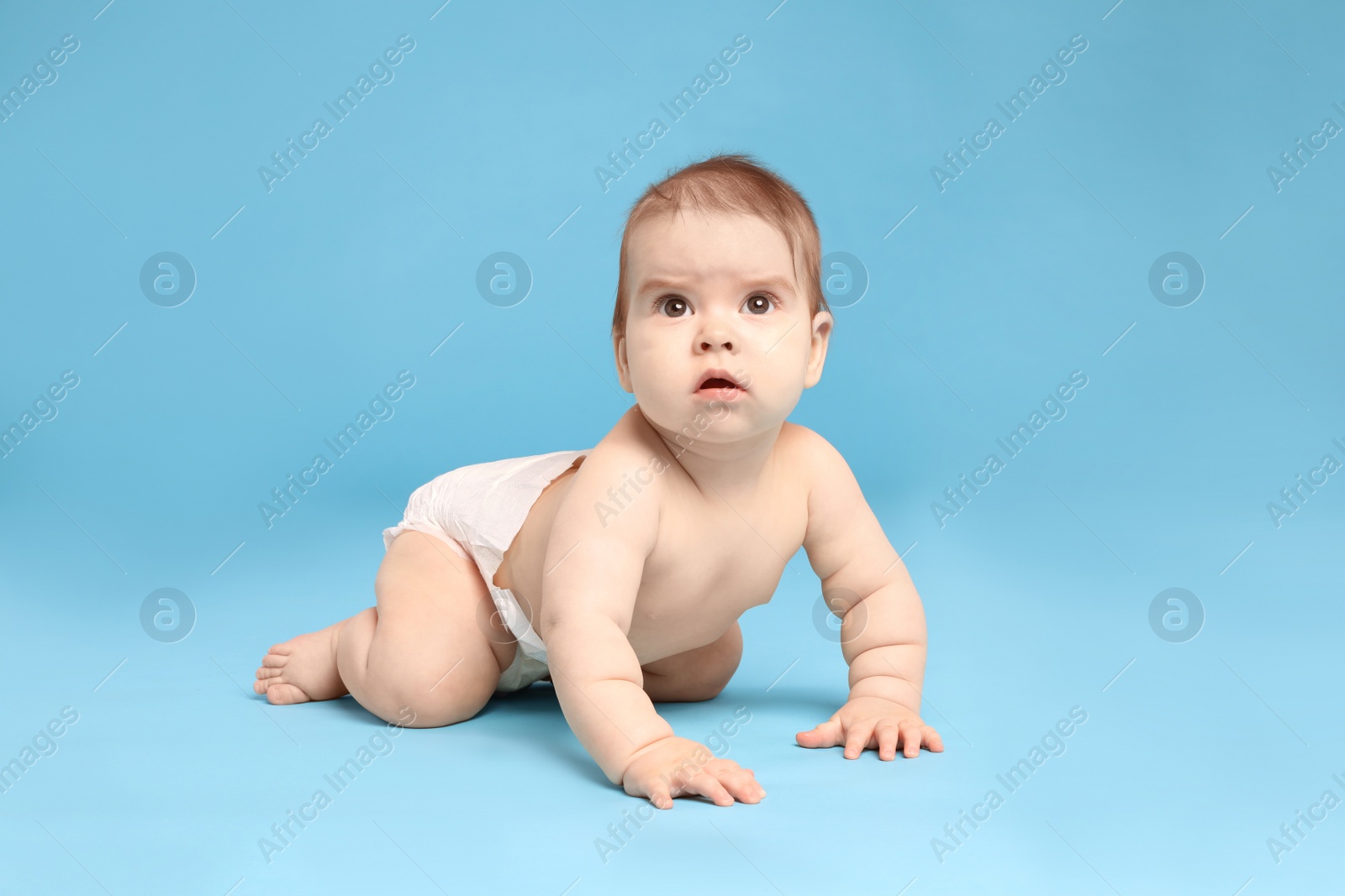 Photo of Cute little baby in diaper crawling on light blue background