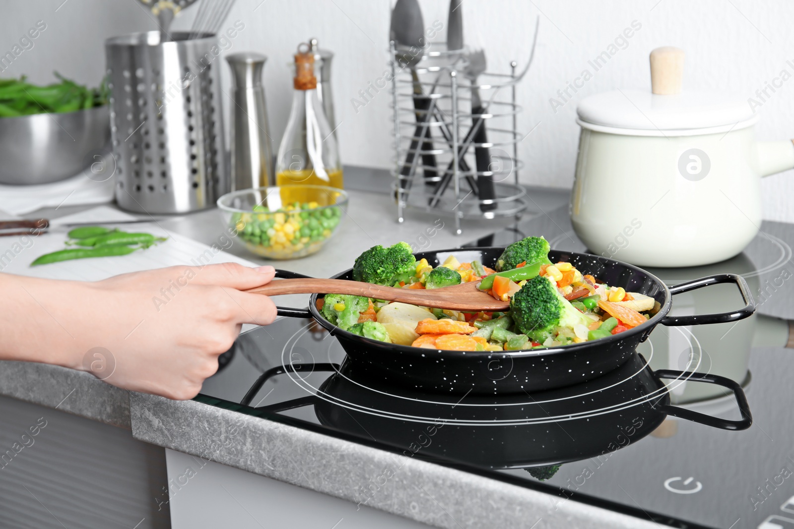 Photo of Woman stirring frozen vegetables on frying pan, closeup