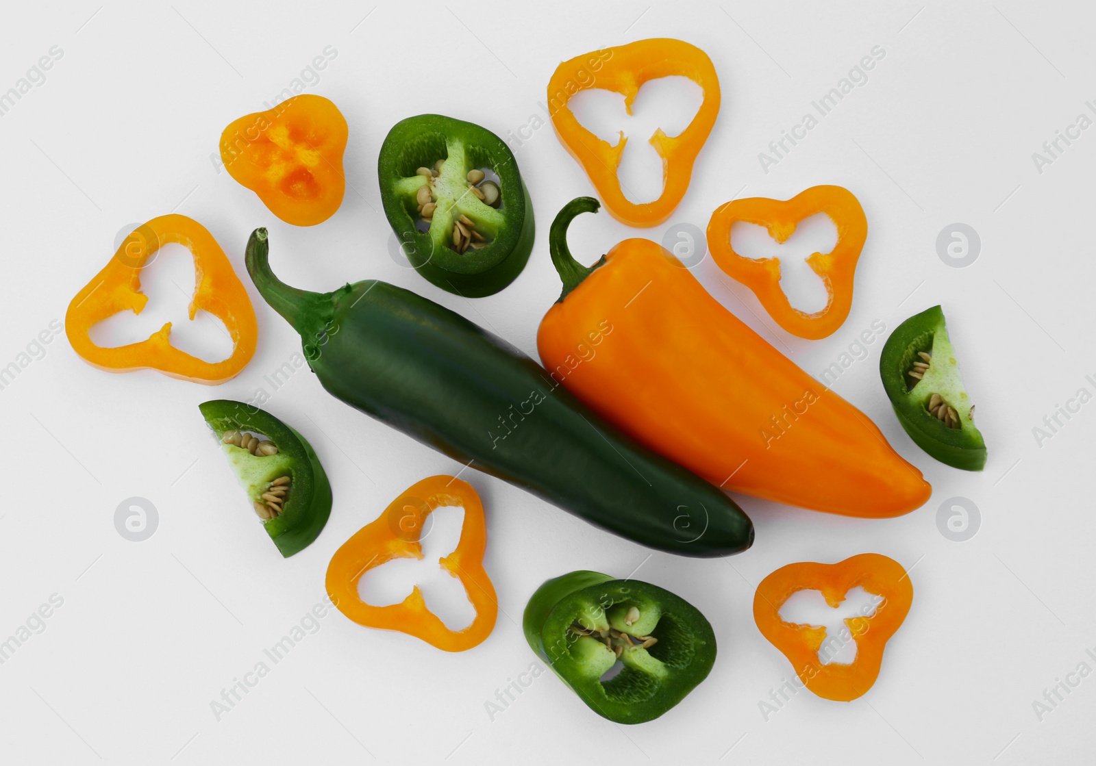 Photo of Different cut and whole hot chili peppers on white background, flat lay