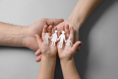 Photo of Parents and child holding paper family figures on gray background, top view