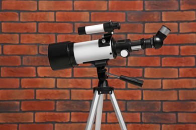 Tripod with modern telescope near brick wall