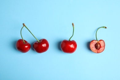 Photo of Cut and whole sweet cherries on light blue background, top view