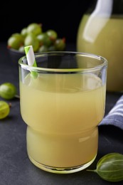 Photo of Tasty gooseberry juice in glass on black table