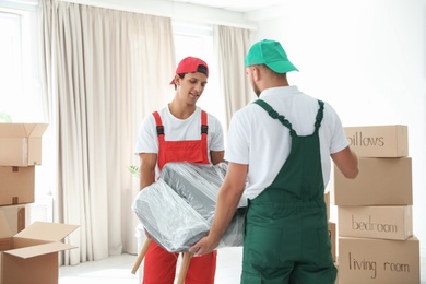 Male movers carrying armchair in new house