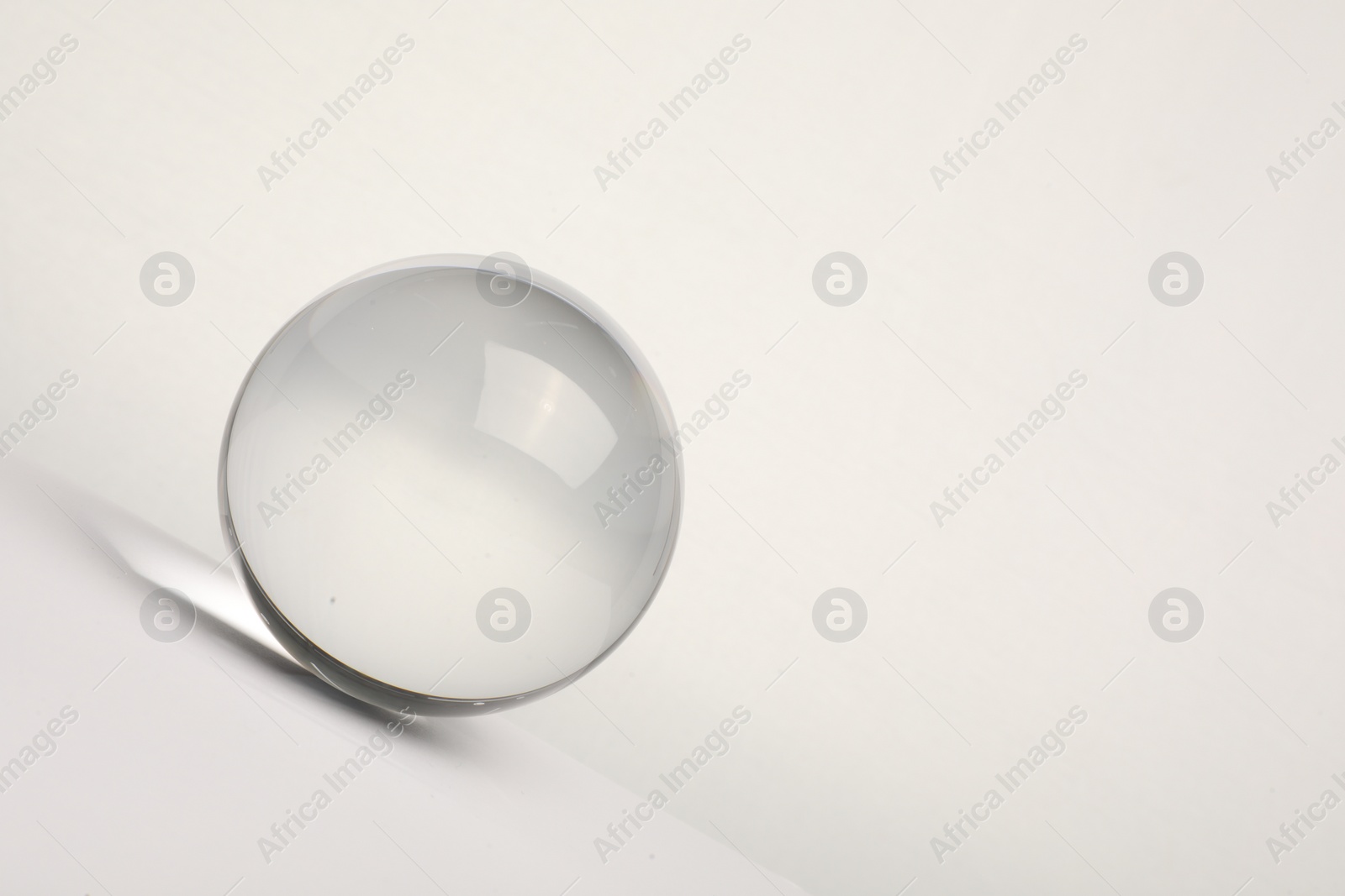 Photo of Transparent glass ball on white background. Space for text