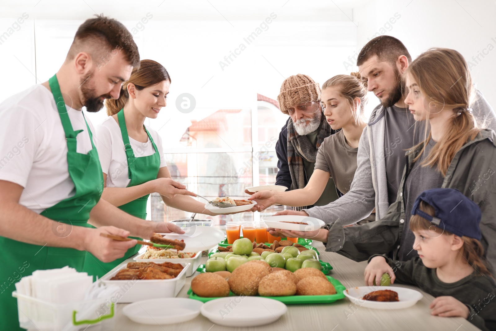 Photo of Poor people receiving food from volunteers indoors