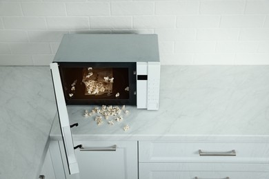 Photo of Open microwave oven with fresh popcorn on countertop in kitchen, above view