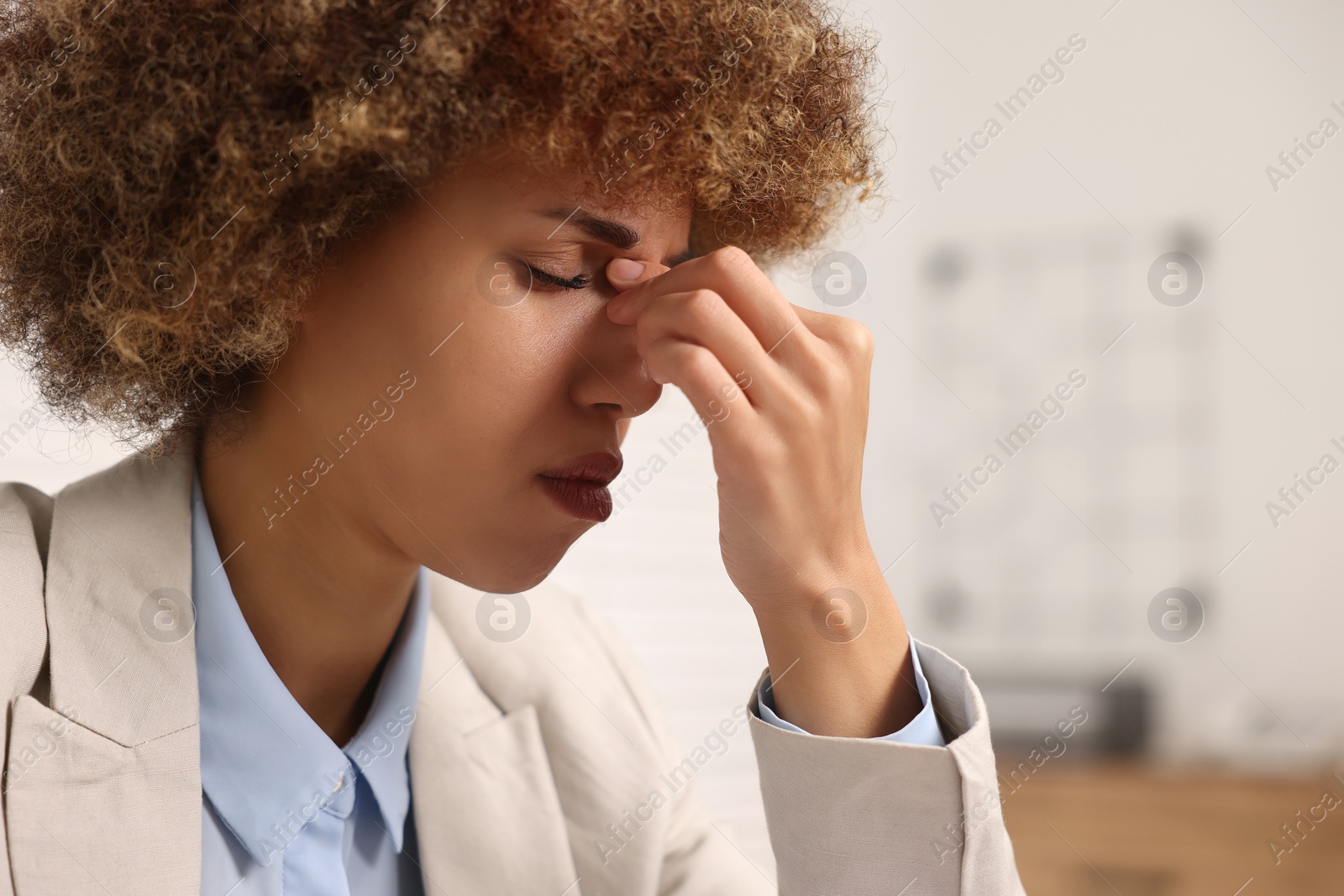 Photo of Young woman suffering from headache in office