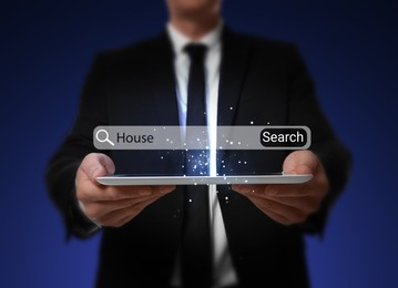 Real estate agent holding tablet on dark blue background, closeup. Virtual search bar with word House over device