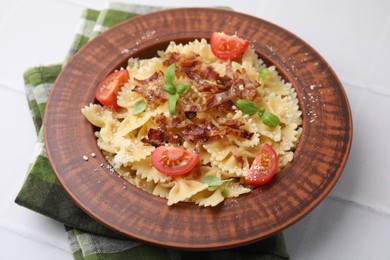 Photo of Tasty pasta with bacon, tomatoes and basil on white tiled table