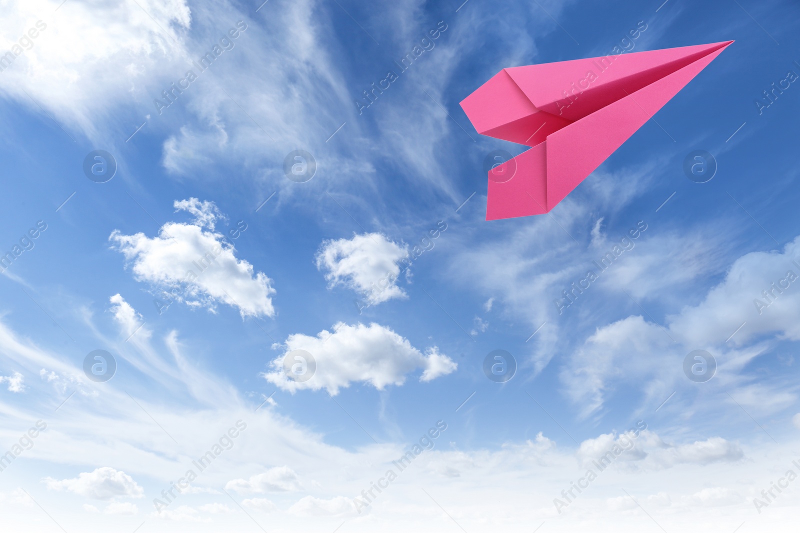 Image of Pink paper plane flying in blue sky with clouds