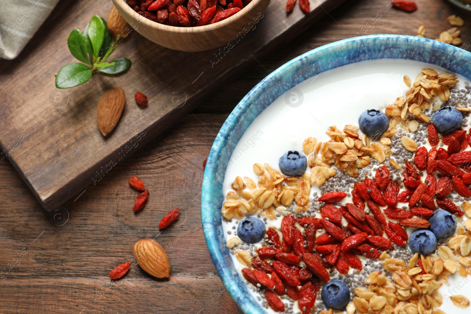 Photo of Smoothie bowl with goji berries on wooden table, closeup