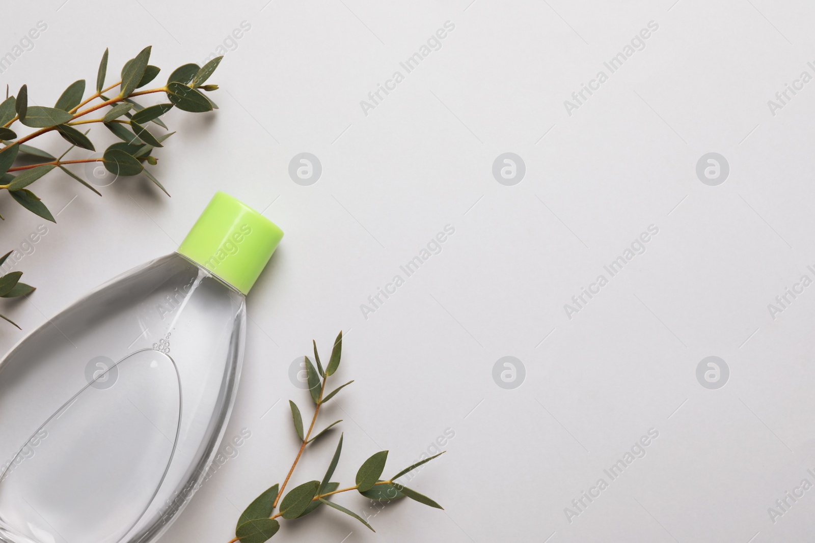 Photo of Bottle of baby oil and leaves on light background, flat lay. Space for text