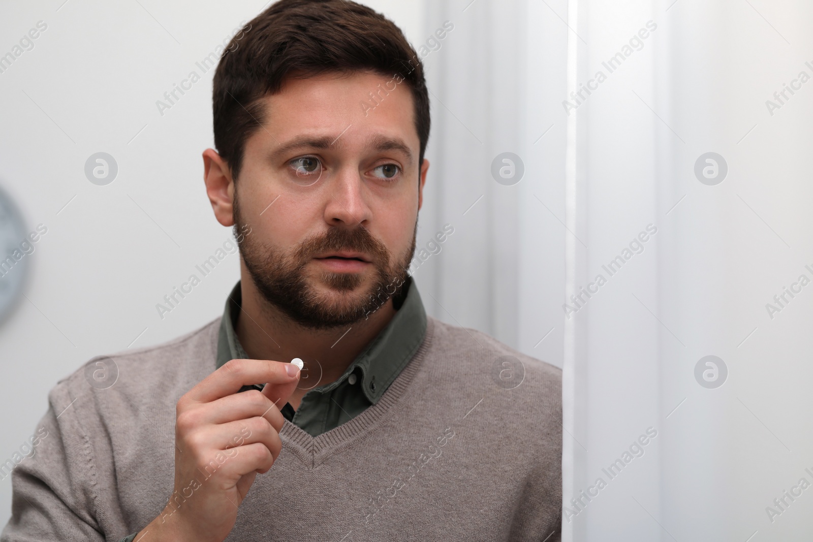 Photo of Depressed man taking antidepressant pill indoors, space for text