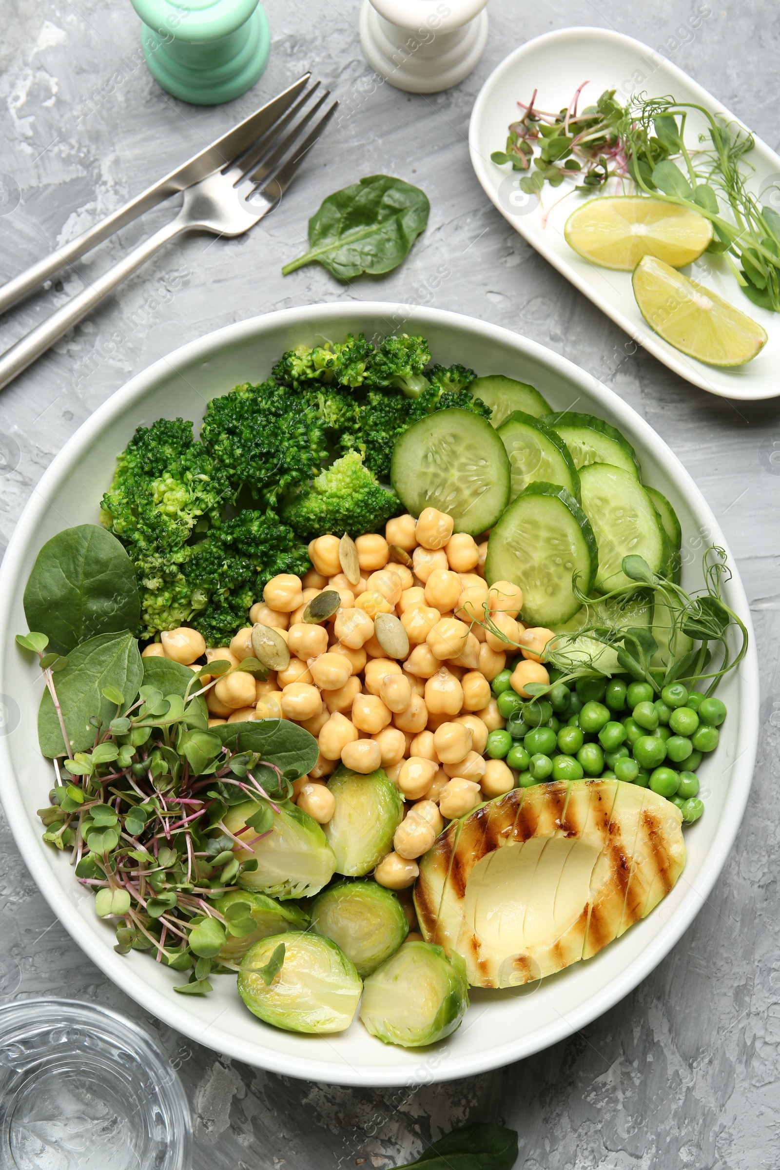 Photo of Healthy meal. Tasty vegetables and chickpeas in bowl on grey table, flat lay