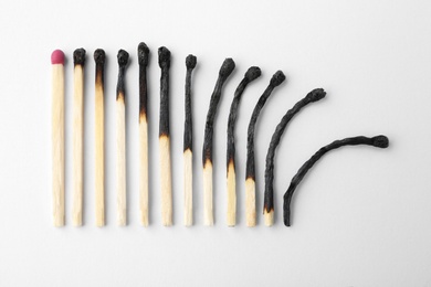 Photo of Row of burnt matches and whole one on white background, top view. Human life phases concept