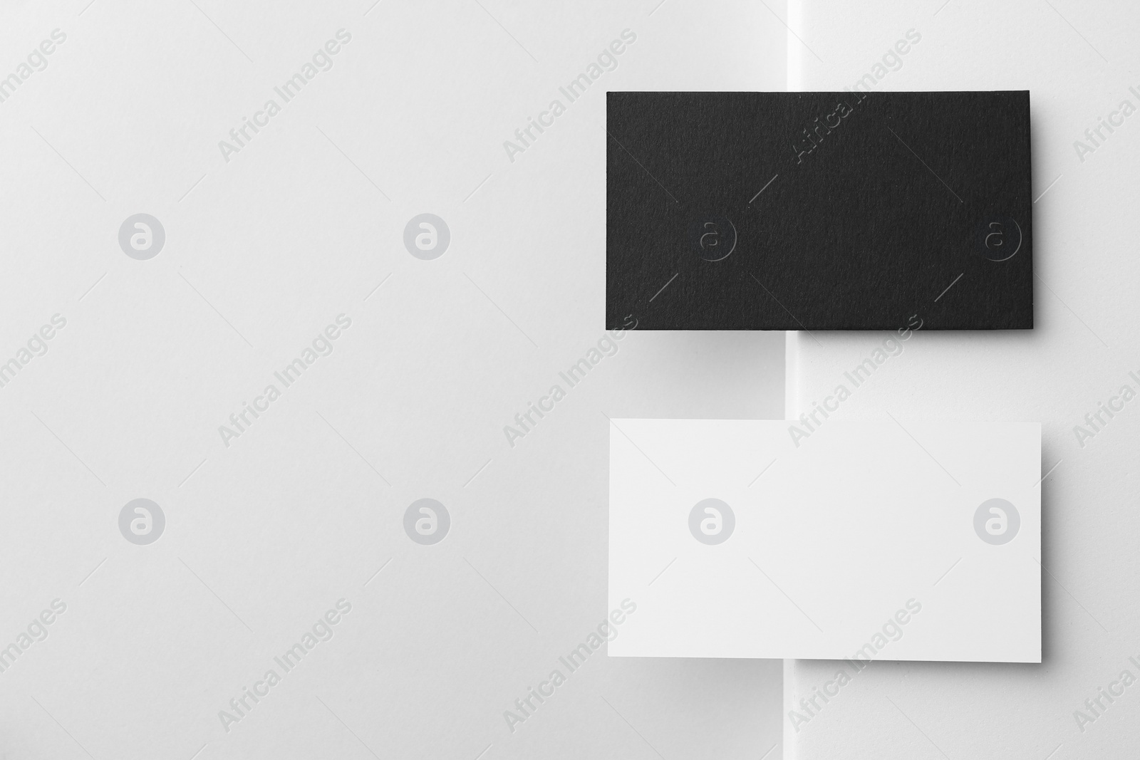 Photo of Blank black and white business cards on light background, flat lay. Mockup for design