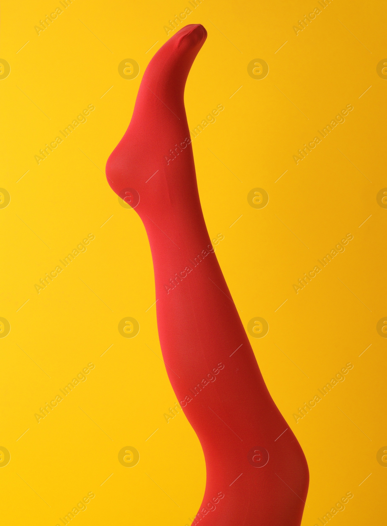 Photo of Leg mannequin in red tights on yellow background