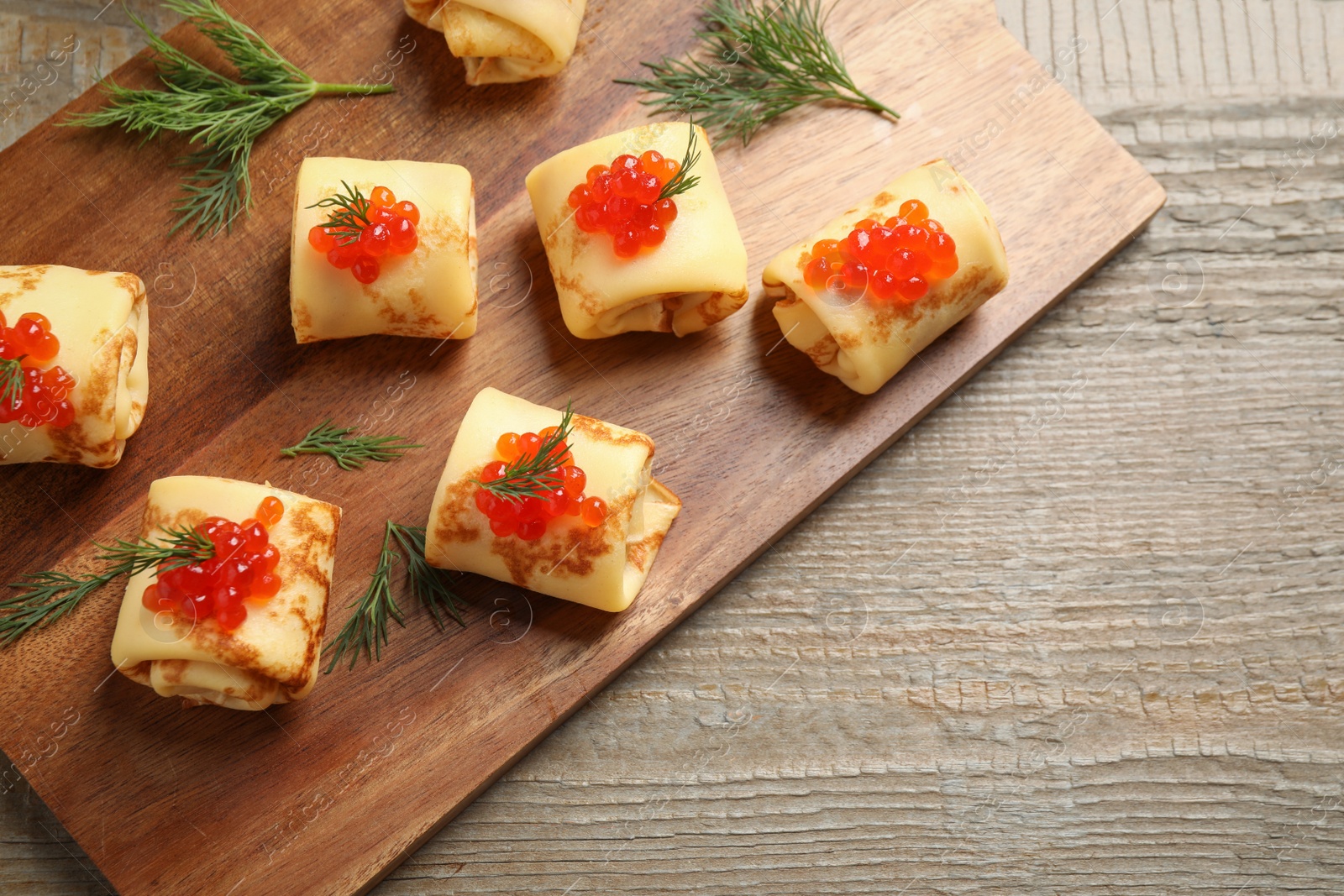 Photo of Delicious thin pancakes with red caviar on wooden table, top view