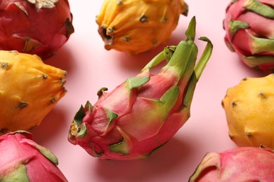 Photo of Different pitahaya fruits on light pink background, closeup