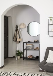 Hallway interior with stylish furniture and round mirror on light wall