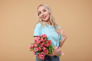 Photo of Happy young woman with beautiful bouquet on beige background