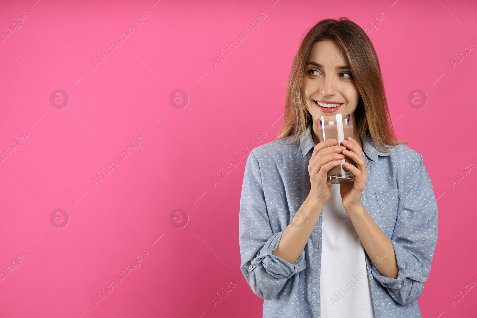 Photo of Young woman drinking chocolate milk on pink background. Space for text