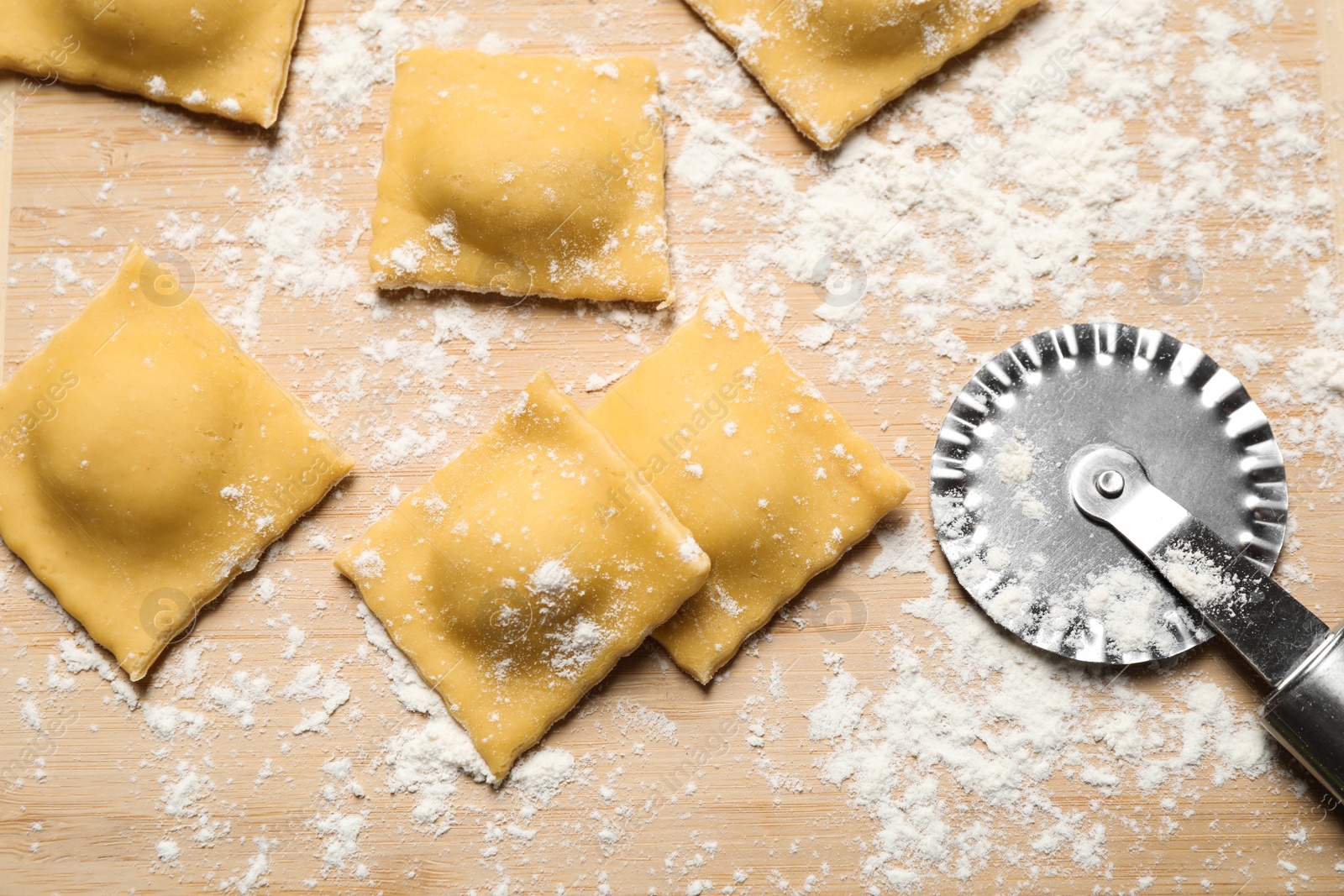 Photo of Raw ravioli on wooden board, flat lay. Italian pasta