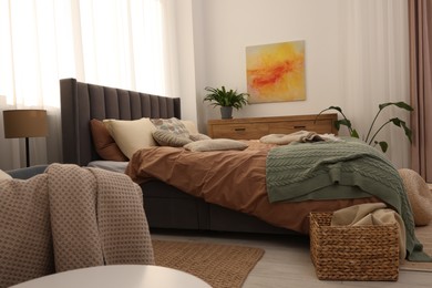 Photo of Large comfortable bed with soft pillows and blanket in room. Home textile