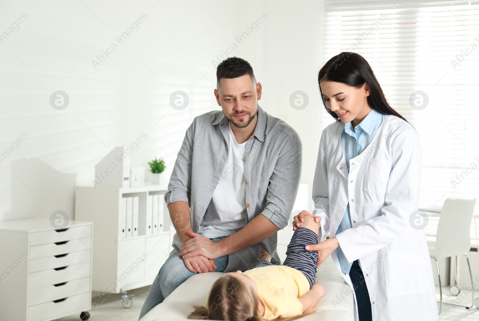 Photo of Professional orthopedist examining little patient's leg in clinic