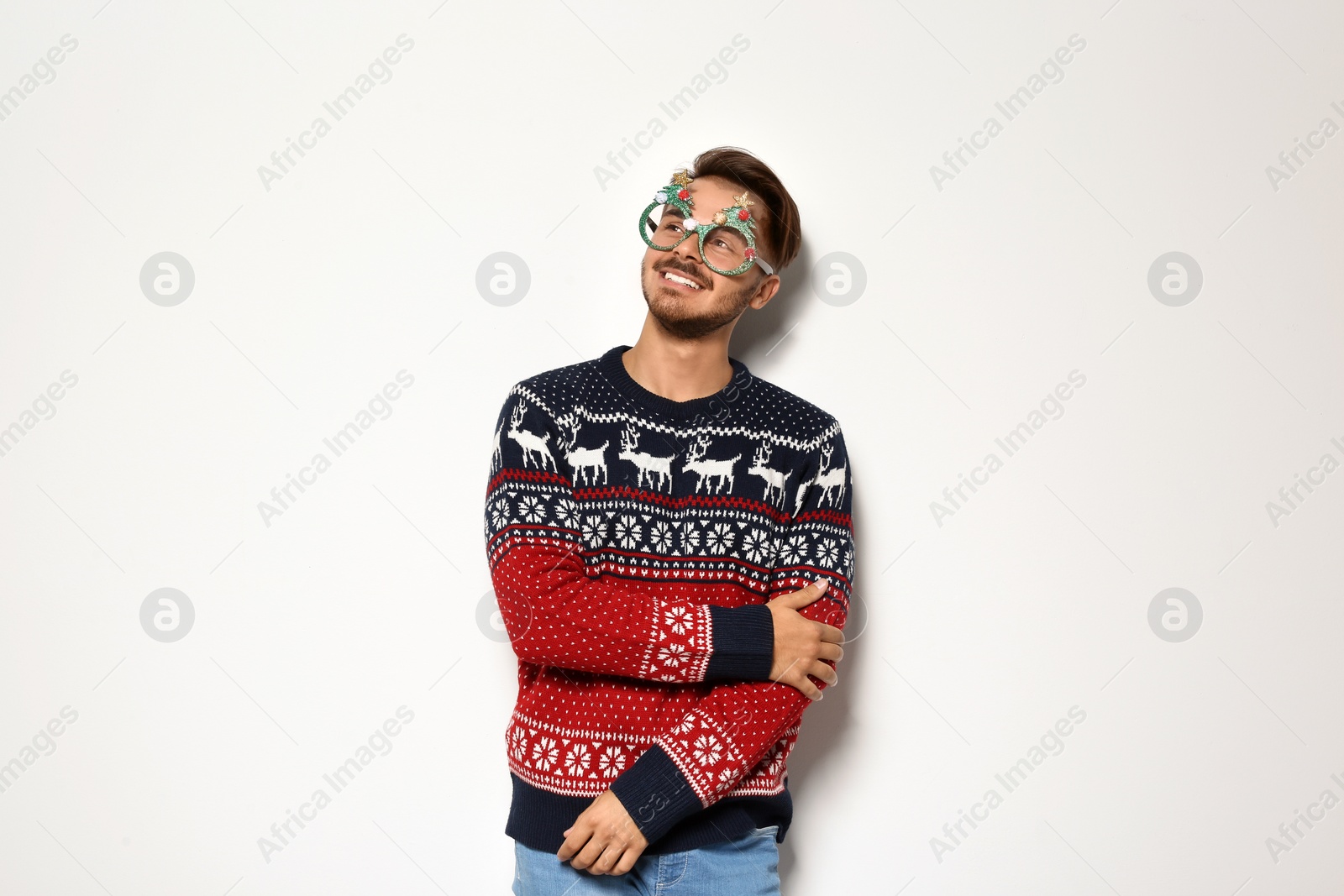 Photo of Young man in Christmas sweater with party glasses on white background