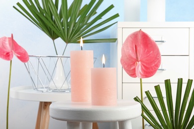 Photo of Creative composition with candles and tropical plants indoors