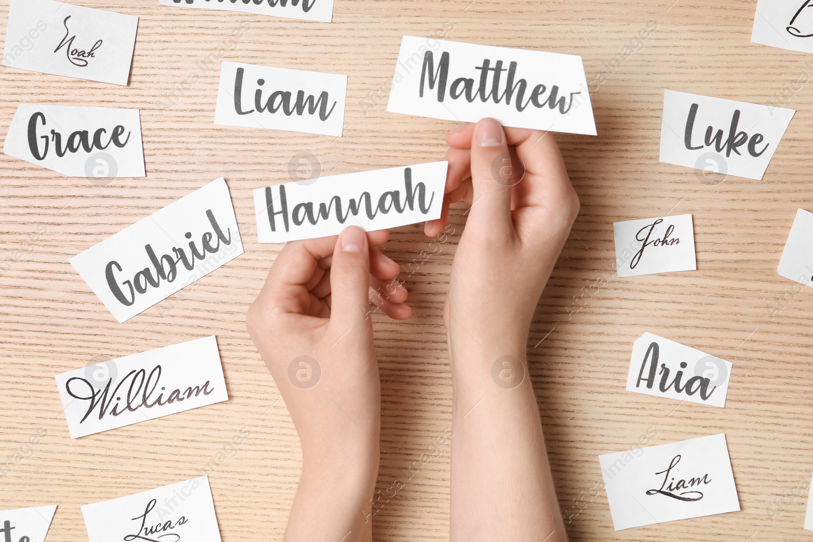 Photo of Woman choosing baby name at wooden table, top view