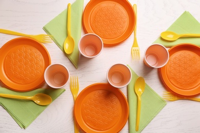 Photo of Composition with plastic dishware on wooden background, flat lay. Picnic table setting