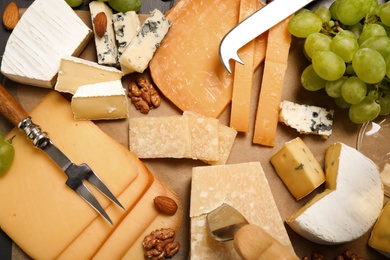 Photo of Flat lay composition with different sorts of cheese and knives on parchment