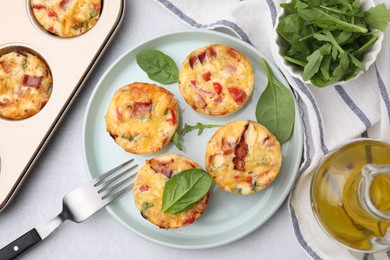 Freshly baked bacon and egg muffins with cheese on light gray table, flat lay