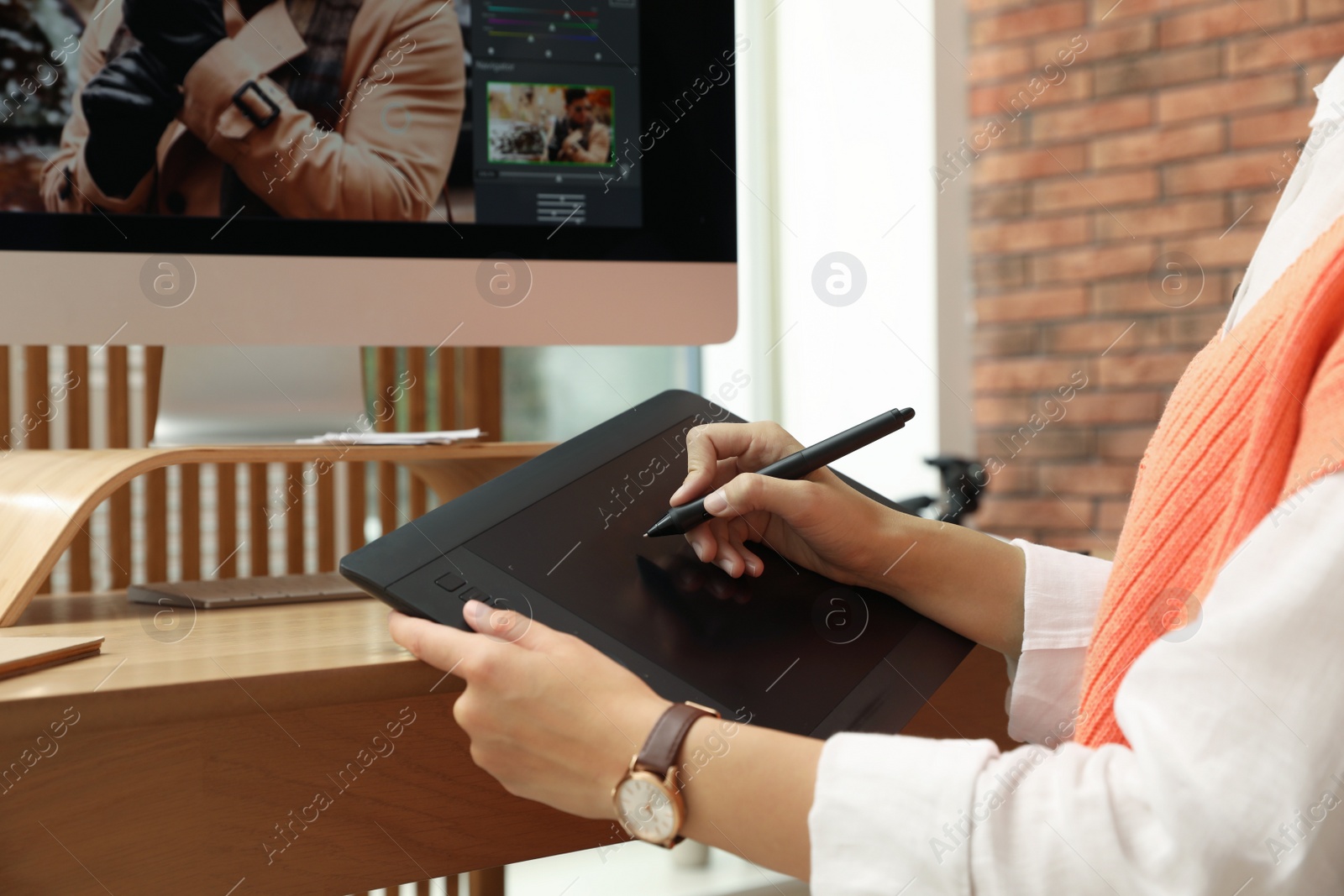 Photo of Professional retoucher working on graphic tablet at desk, closeup