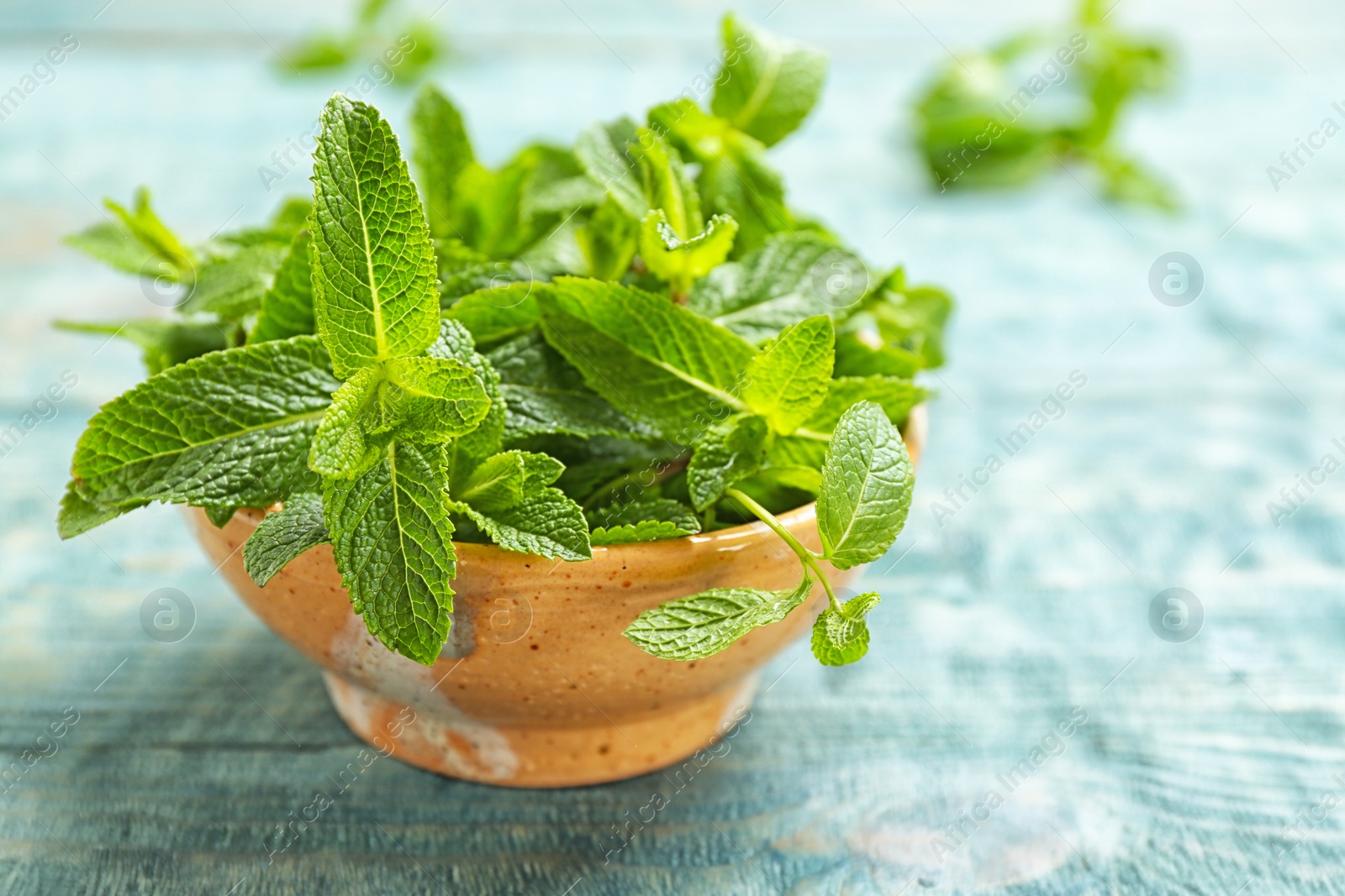 Photo of Bowl with fresh aromatic mint on table