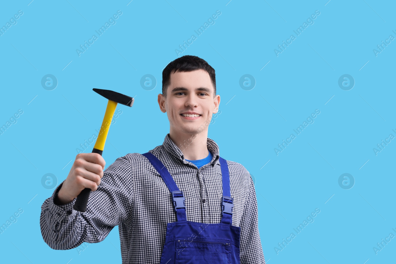 Photo of Professional repairman holding hammer on light blue background. Space for text