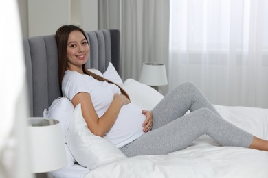 Beautiful pregnant woman with long hair in bedroom