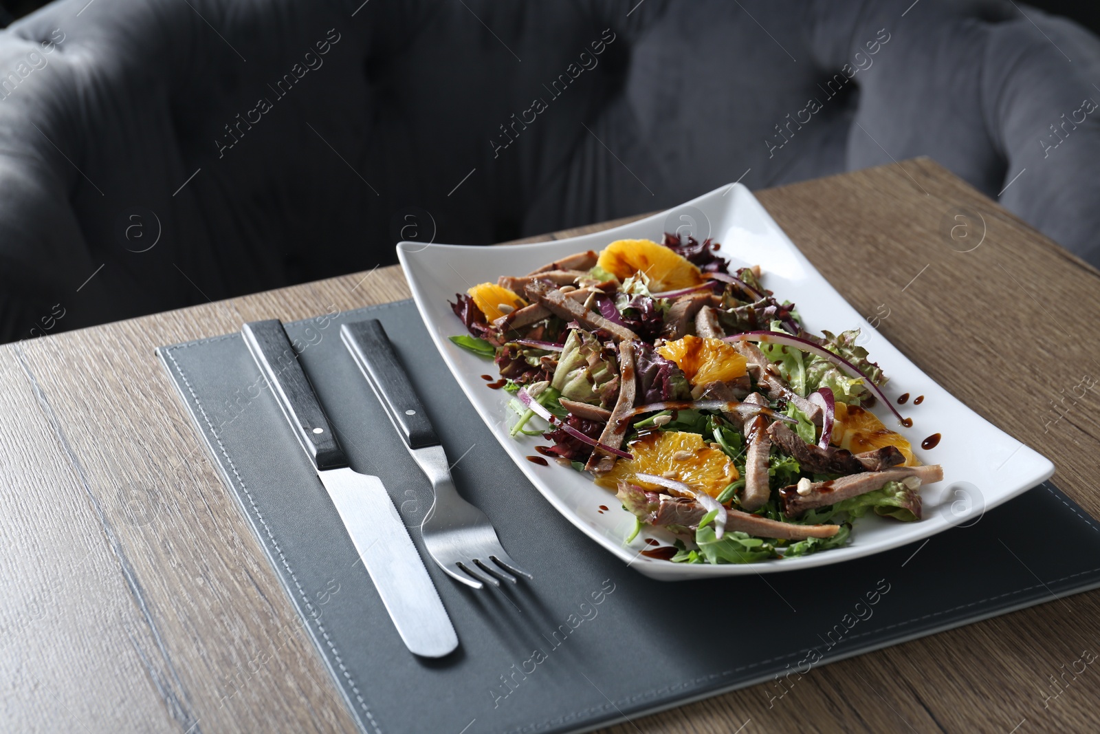 Photo of Delicious salad with beef tongue, orange and onion served on wooden table