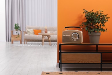 Photo of Retro radio receiver and houseplant on console table in stylish hallway, space for text. Interior design