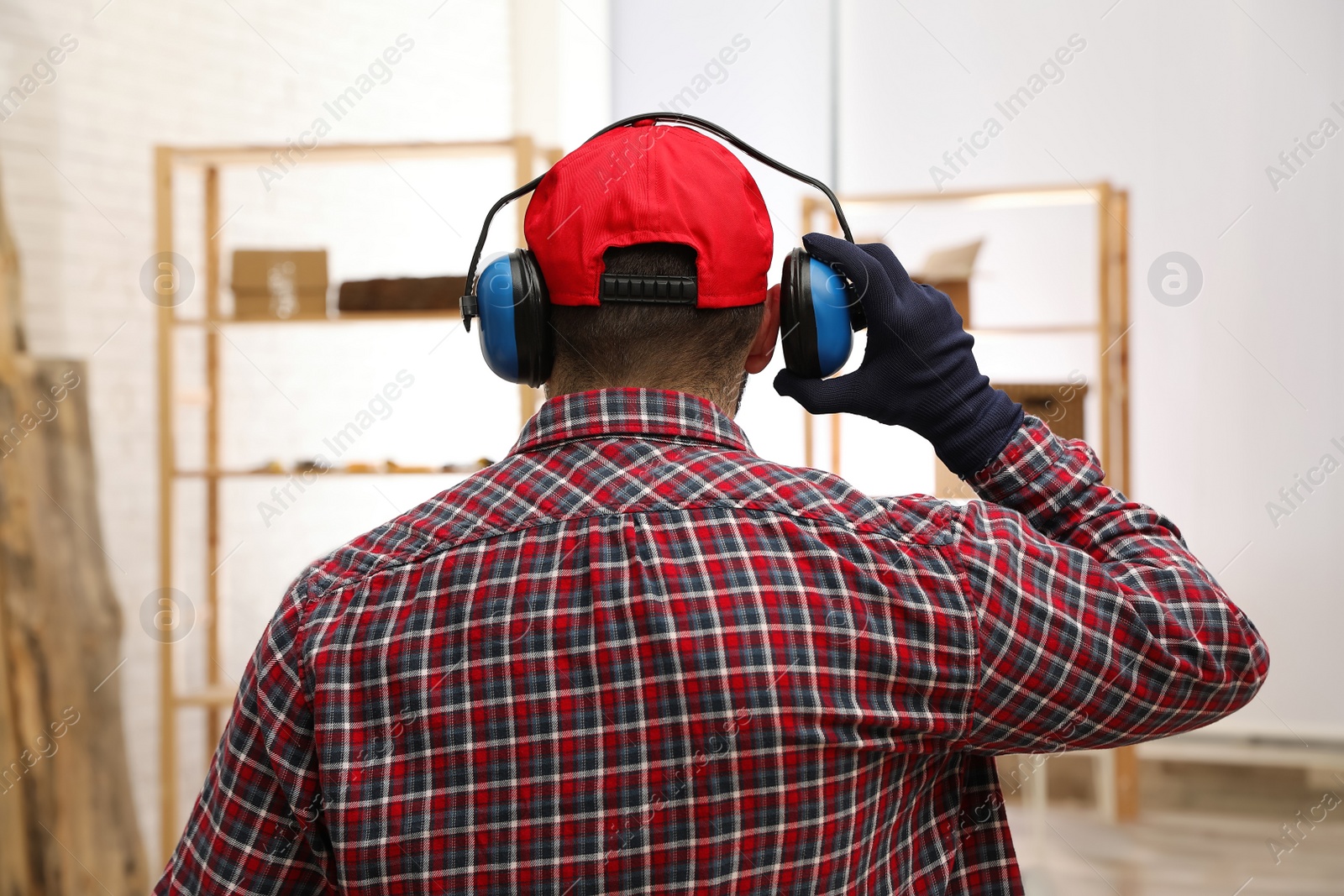 Photo of Worker wearing safety headphones indoors, back view. Hearing protection device