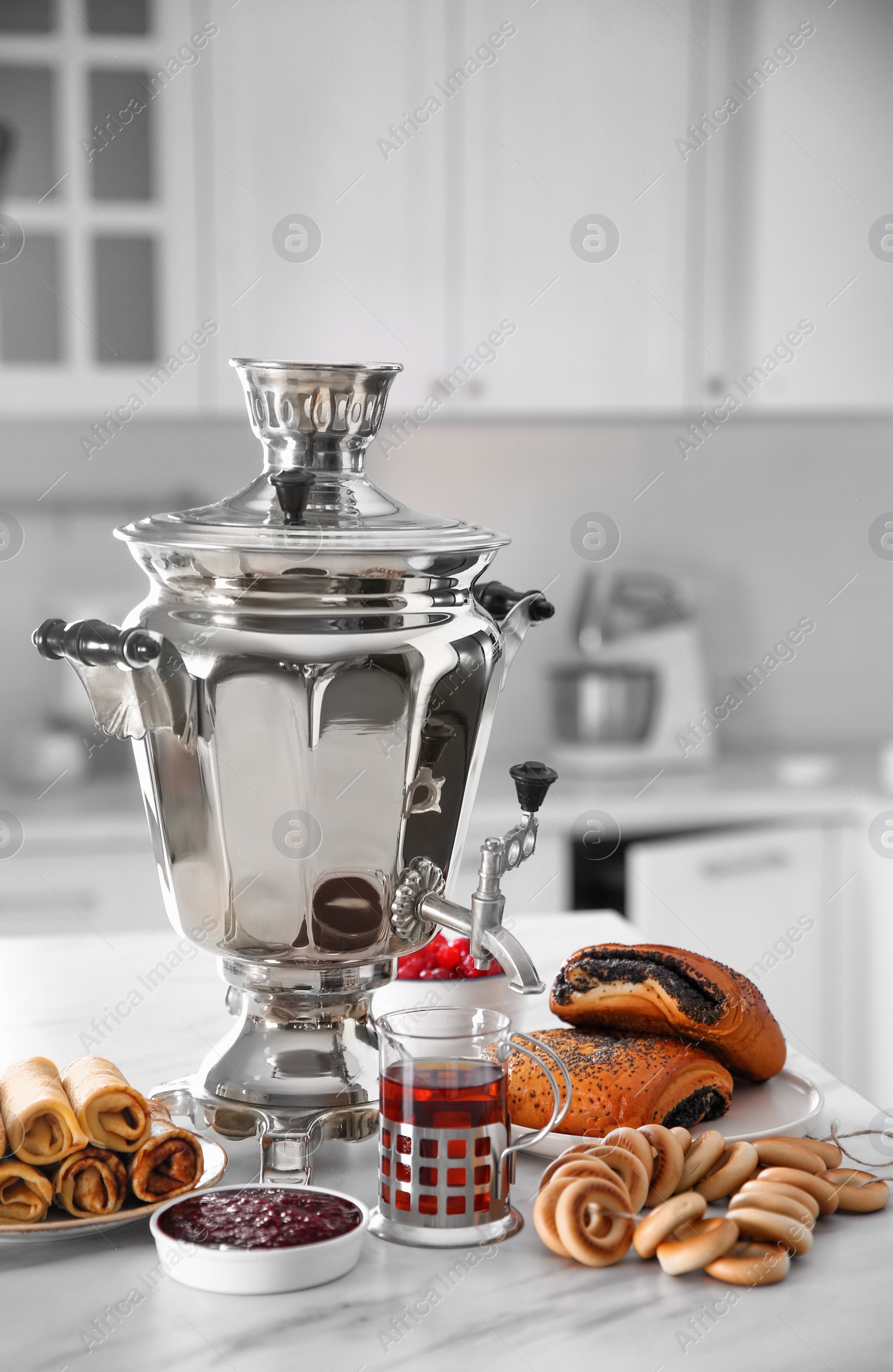 Photo of Traditional Russian samovar and treats on white table in kitchen