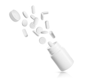 Image of Many different pills bursting out of bottle on white background
